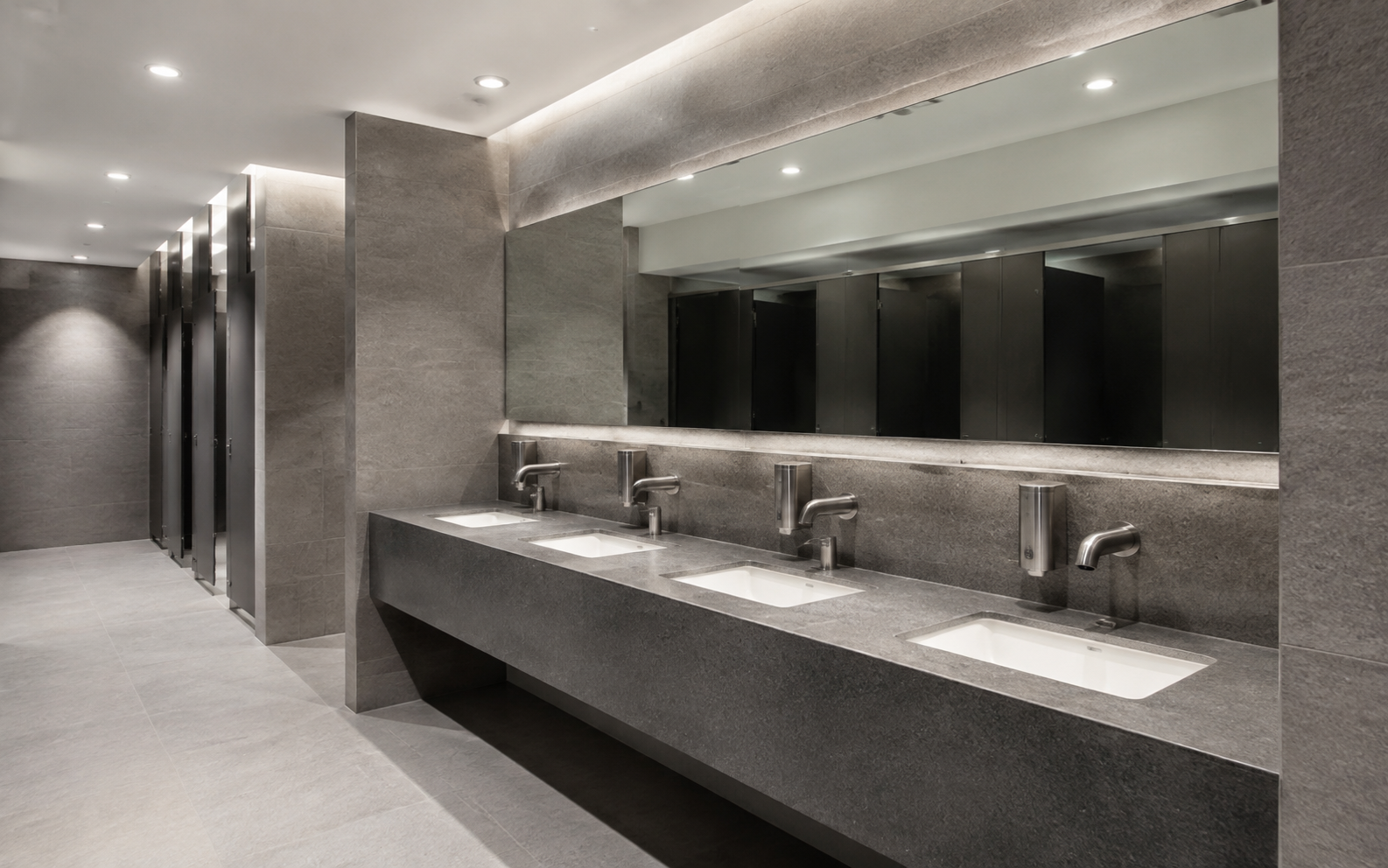 Long bathroom mirror above multiple basins in a commercial washroom