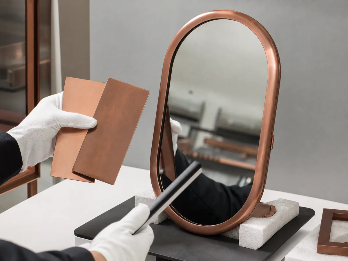 Concept of copper finish samples being compared with a pill-shaped framed mirror under inspection light